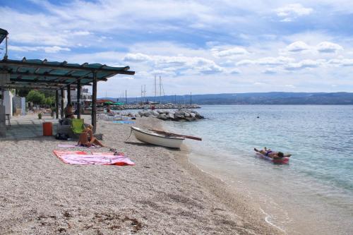 a group of people sitting on a beach near the water at Apartments by the sea Sumpetar, Omis - 4827 in Jesenice