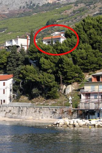 a house on a hill with a red circle on it at Apartments by the sea Sumpetar, Omis - 4827 in Jesenice