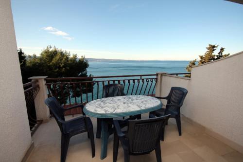 a table and chairs on a balcony with the ocean at Apartments by the sea Sumpetar, Omis - 4827 in Jesenice