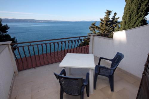 a table and two chairs on a balcony with the ocean at Apartments by the sea Sumpetar, Omis - 4827 in Jesenice