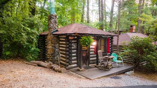 eine Hütte im Wald mit einem Tisch und Stühlen in der Unterkunft Log Cabin Motor Court in Asheville