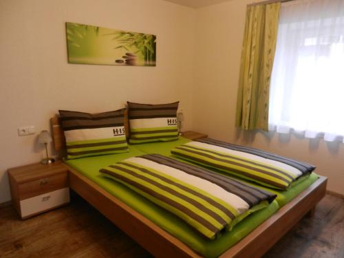 łóżko z zieloną i białą pościelą oraz oknem w obiekcie Ferienhaus Sporer w mieście Iselsberg