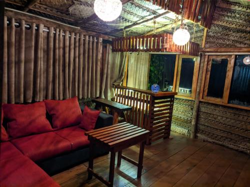 a living room with a red couch and a table at La Luna Cabins in Nuwara Eliya