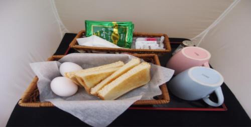 a basket with eggs and bread and a candle and a cup at ホテルセーラ伊勢崎店大人専用 in Isesaki