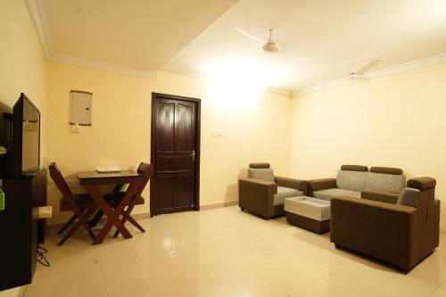 a living room with a couch and chairs and a table at K V Suites in Cochin