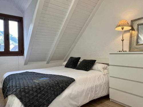 1 dormitorio con cama blanca y almohadas negras en Locky · Espacio y Exclusividad ❅ Pirineos360 ❅, en Sallent de Gállego