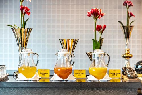 Una mesa con tres jarrones llenos de jugo de naranja. en Ramada Hotel and Suites Seoul Namdaemun, en Seúl