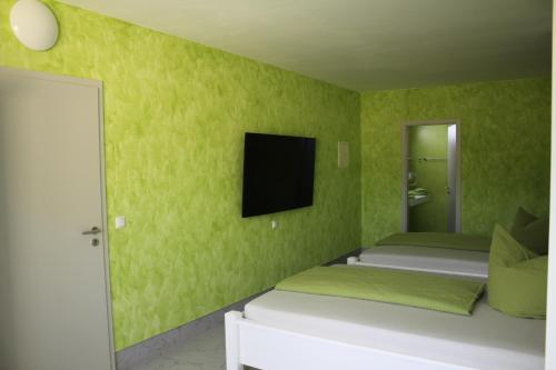 a green room with two beds and a flat screen tv at Hotel/Pension Rast& Ruh in Zodel