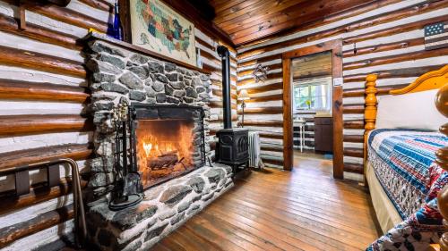 a log cabin with a fireplace in a bedroom at Log Cabin Motor Court in Asheville