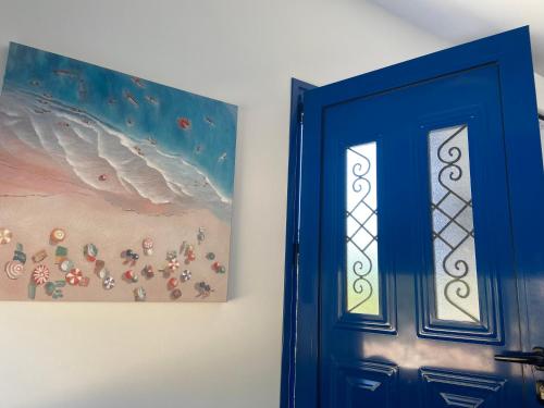a blue door next to a painting of a beach at Villa Edna Crete in Agios Nikolaos