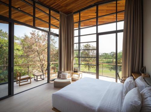 a bedroom with a bed and large windows at Gliding Villa in Khao Yai in Mu Si