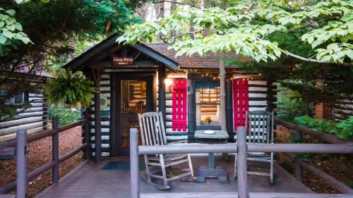 a small house with red doors and two chairs at Log Cabin Motor Court in Asheville
