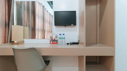 Habitación con escritorio, TV y silla. en RedDoorz Near Iloilo International Airport en Iloílo