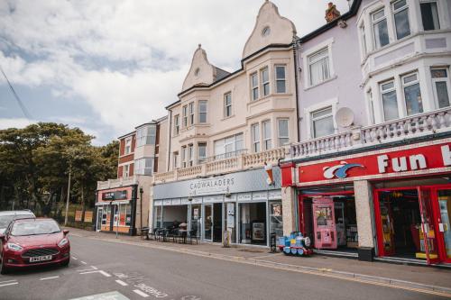 a row of buildings on a city street with a car at Barry Island Beachfront Apartment - Stunning Bay Views and Private Parking in Barry