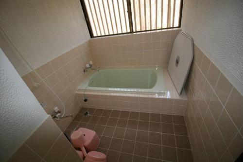 a bathroom with a tub and a pink toilet at 北軽井沢の貸別荘一棟貸し切り-庭とウッドデッキつき in Azumaiokozan