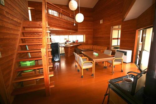 a dining room with a table and chairs and a staircase at 北軽井沢の貸別荘一棟貸し切り-庭とウッドデッキつき in Azumaiokozan
