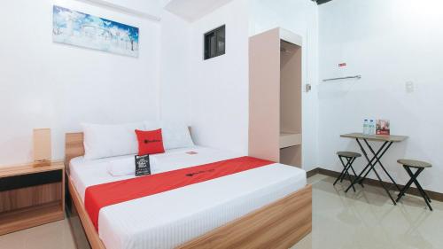 1 dormitorio con cama y mesa pequeña en RedDoorz Near Iloilo International Airport, en Iloilo City