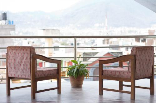two chairs and a potted plant on a balcony at Hotel Yambu kathmandu in Kathmandu