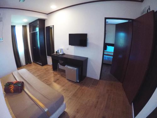 ein Hotelzimmer mit einem Bett und einem TV in der Unterkunft Anjung Villa in Pantai Cenang