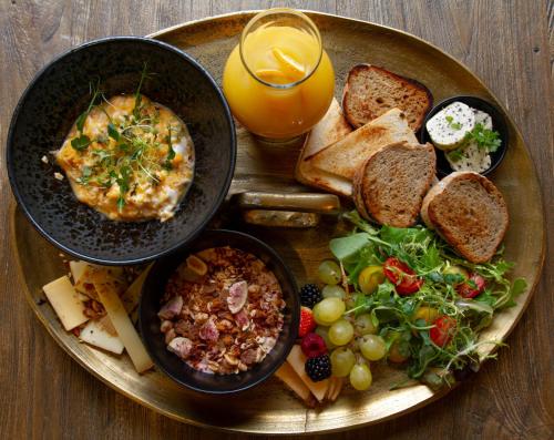 a plate of food with eggs and bread and a glass of orange juice at Royal Apartmány in Dobříš