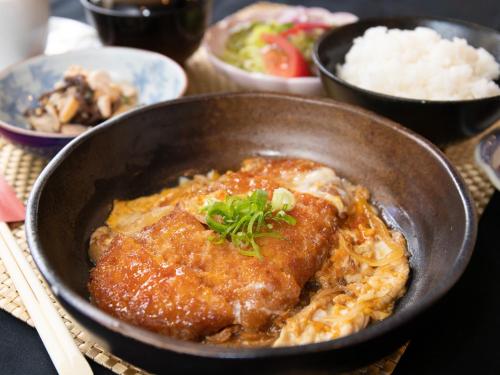 a bowl of food with meat and rice on a table at Tabist Sasebo Palace Hotel in Sasebo