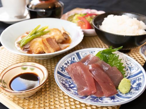 a table topped with plates of food and rice at Tabist Sasebo Palace Hotel in Sasebo