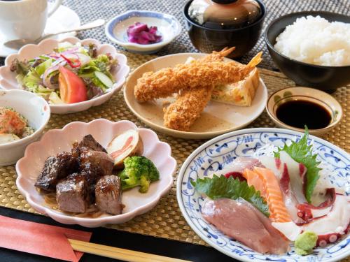 a table topped with plates of food and bowls of food at Tabist Sasebo Palace Hotel in Sasebo