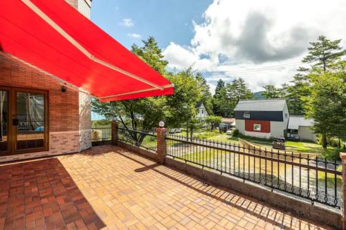 a house with a red awning and a fence at Seventh Heaven Hakuba in Hakuba