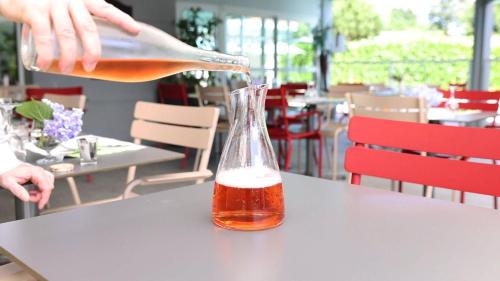 a person is pouring a drink into a glass on a table at Abor Hôtel, Mont de Marsan in Saint-Pierre-du-Mont