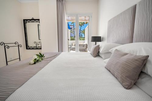 a white bedroom with a large bed and a mirror at Apartamento de 2 dormitorios en Las Gaviotas - Puerto Banús in Marbella