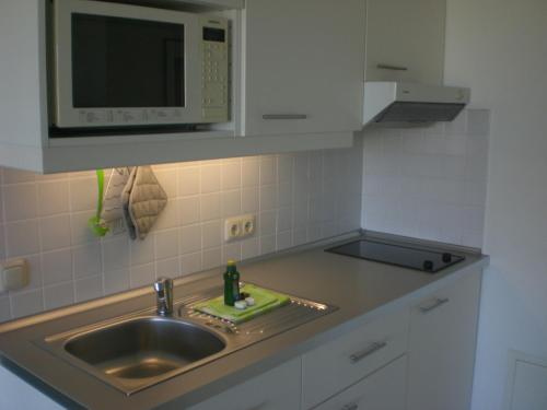 eine Küche mit einer Spüle und einer Mikrowelle in der Unterkunft Jan und Jana Ferienhaus in Ahrenshoop