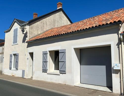 a white house with a large garage at Villa Paulownia - à 1,2km des plages - tout confort au coeur du bourg in Jard-sur-Mer