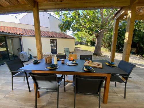 a table with chairs and food on it on a patio at Villa Paulownia - à 1,2km des plages - tout confort au coeur du bourg in Jard-sur-Mer