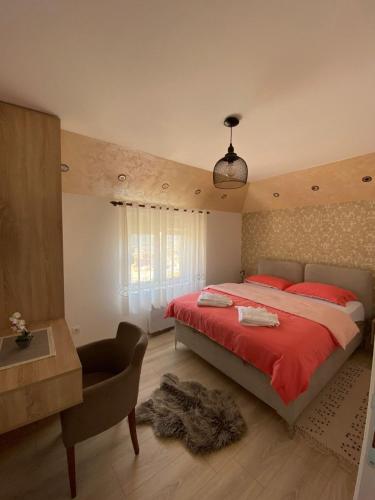 a bedroom with a red bed and a desk and a chair at Apartman Zara Zlatar in Nova Varoš