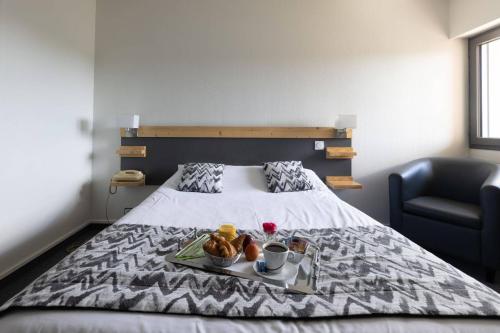 a bedroom with a bed with a tray of food on it at Abor Hôtel, Mont de Marsan in Saint-Pierre-du-Mont