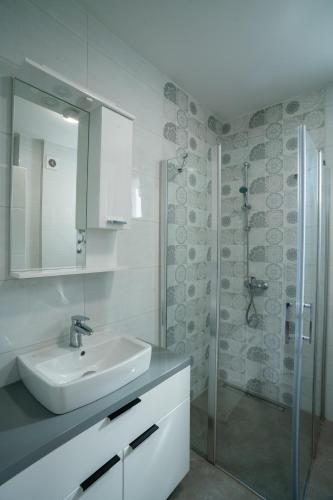a white bathroom with a sink and a shower at Apartman Pale centar Free parking in Pale