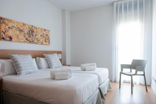duas camas num quarto de hotel com paredes brancas em Apartamentos Aura Park Fira BCN em Hospitalet de Llobregat