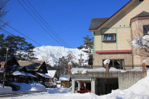 a house covered in snow with a mountain in the background at Seventh Heaven Hakuba in Hakuba