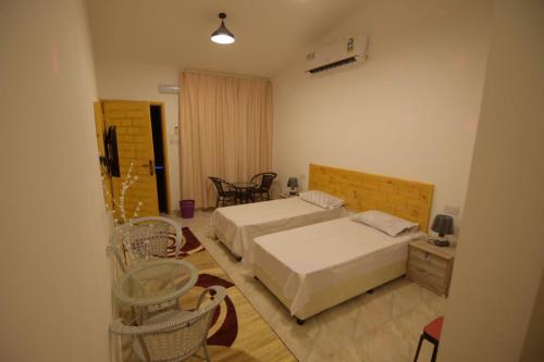 1 Schlafzimmer mit 2 Betten, einem Tisch und Stühlen in der Unterkunft السكون لبيوت الضيافة و شاليه AL Sukun For Guest Houses & Chalet in Ras al-Hadd