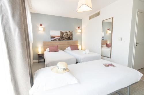 a room with three beds and a mirror at Comfort Aparthotel Cannes Mandelieu in Mandelieu-la-Napoule