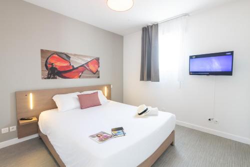 a bedroom with a large white bed and a flat screen tv at Comfort Aparthotel Cannes Mandelieu in Mandelieu-la-Napoule