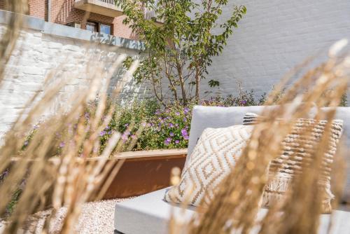 eine Terrasse mit einem Sofa und einigen Pflanzen in der Unterkunft Maison Odett - fully renovated house for 10 people in Nieuwpoort