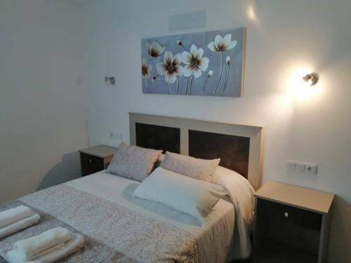 een slaapkamer met een bed met 2 tafels en een schilderij bij 3Arguineguin terrasse apart next to beach in Arguineguín