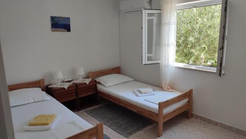 two twin beds in a room with a window at Apartmani Vinko Bol in Bol