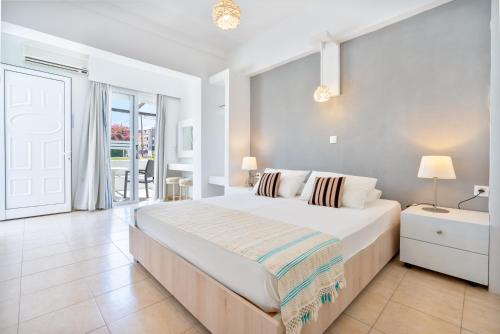 a white bedroom with a large bed and a window at Mando Living -Faliraki in Faliraki