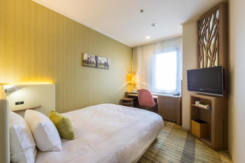 a hotel room with a bed and a television at Kichijoji Excel Hotel Tokyu in Musashino