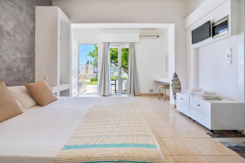 a white bedroom with a large bed and a sliding glass door at Mando Living -Faliraki in Faliraki