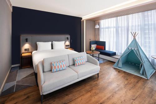 sypialnia z łóżkiem i kanapą w pokoju w obiekcie Holiday Inn Express Qingdao Jinshui, an IHG Hotel w mieście Qingdao