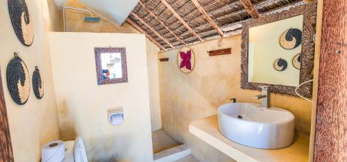 a bathroom with a sink and a mirror at Ananda Beach Hotel in Paje