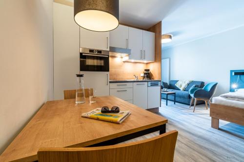 a kitchen and living room with a wooden dining table at Ostsee Apartmenthotel in Graal-Müritz